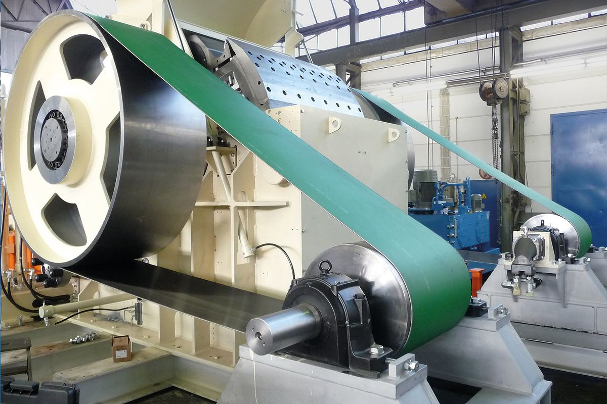 Groene aandrijfriem over een grote riemschijf en een tweede schijf op lagerblokken, bij een industriële machine